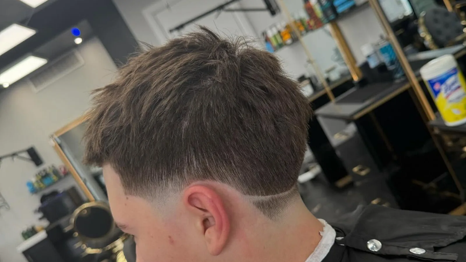 Barber detailing a short men's haircut with scissor over comb